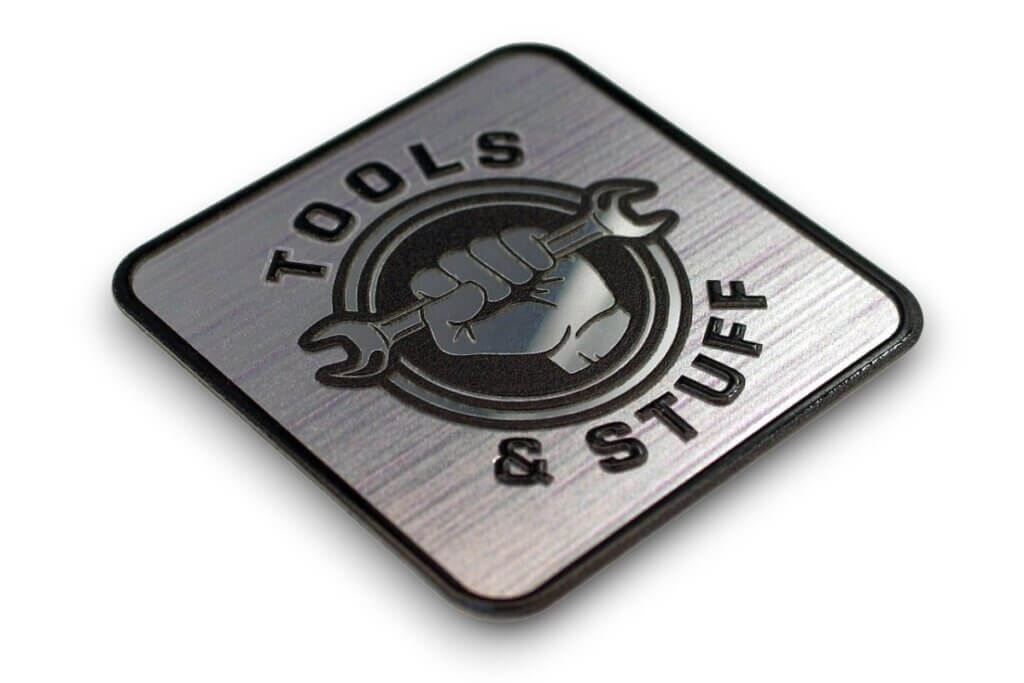 A company nameplate for a product with a silver background and black print and Tools & Stuff logo